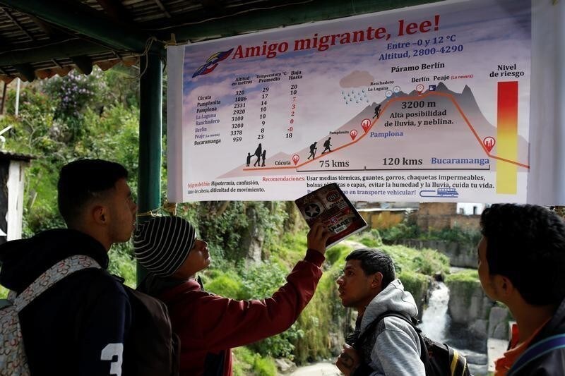 Undocumented Venezuelan migrants look at a banner with information about the route from Cucuta to Bucaramanga at a makeshift shelter for Venezuelan migrants in Pamplona, Colombia August 25, 2018. The majority of the migrants have never left Venezuela and sometimes struggled to understand the magnitude of the journey ahead.