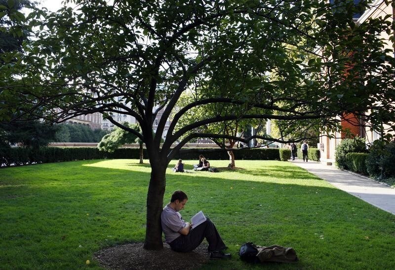 A student sits under a tree to read on the campus of Columbia University in New York, October 5, 2009.