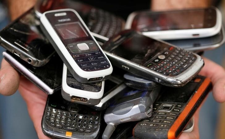 A worker of Ecomicro recycling company holds old cell phones in Saint Loubes near Bordeaux, Southwestern France, July 4, 2017. REUTERS/Regis Duvignau