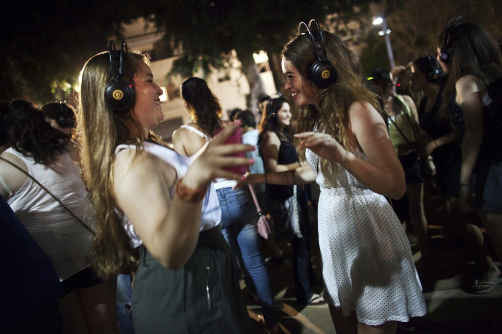 Women dance while listening to music on wireless earphones during a "Silent Disco", in a main boulevard in Tel Aviv during the "White Night" festival June 30, 2011. The annual festival celebrates Tel Aviv being listed as a UNESCO World Heritage site in July 2003. Picture taken June 30, 2011. REUTERS/Nir Elias (ISRAEL - Tags: ENTERTAINMENT SOCIETY) - GM1E7711JL501