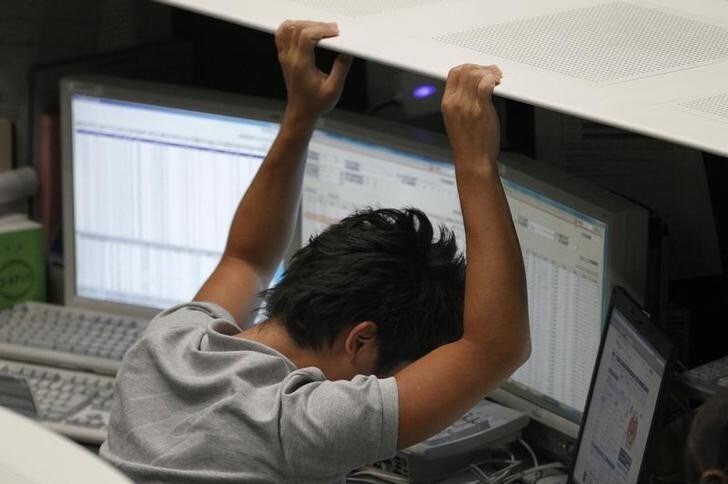 An employee of the Tokyo Stock Exchange (TSE) reacts as he works at the bourse in Tokyo August 9, 2011. The Nikkei stock average closed down 1.7 percent on Tuesday, having trimmed losses on bargain hunting after the index tumbled more than 4 percent in the wake of a plunge on Wall Street and a downgrade of U.S. sovereign debt. REUTERS/Kim Kyung-Hoon (JAPAN - Tags: BUSINESS)