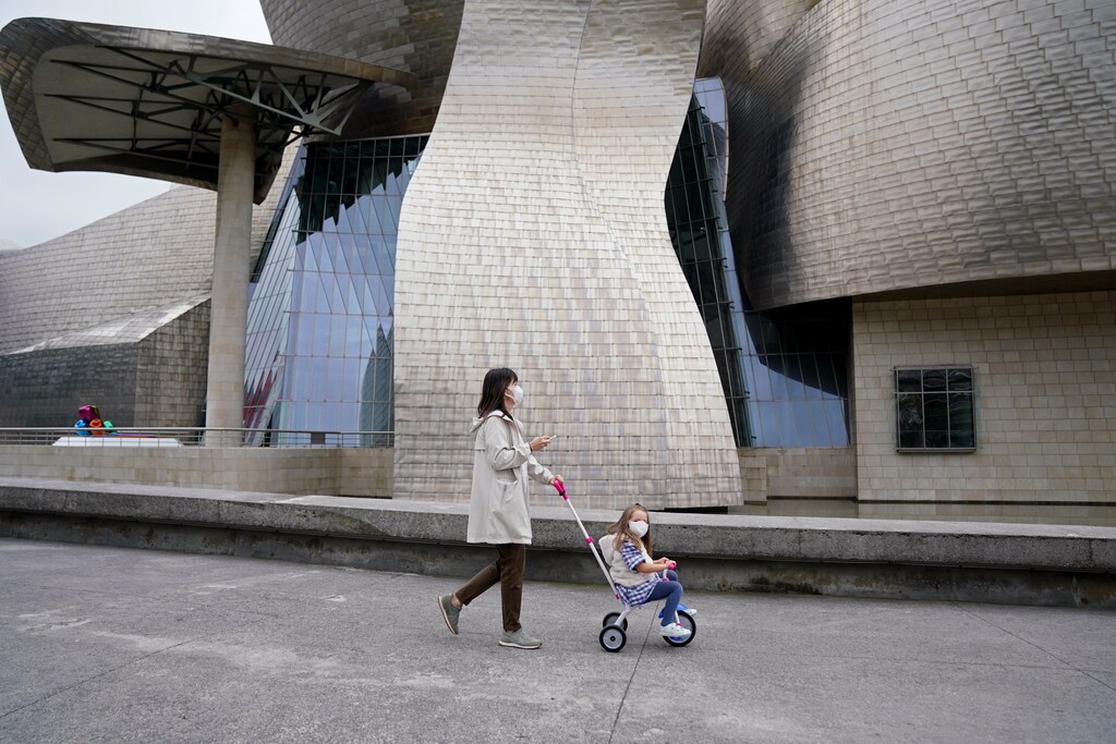 Una madre y su hijo pasan por el Museo Guggenheim, después de que se levantaran parcialmente las restricciones para los niños por primera vez en seis semanas, durante el brote de la enfermedad coronavirus (COVID-19) en Bilbao, España, el 26 de abril de 2020.