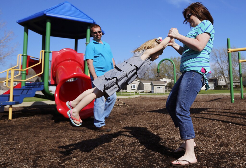 Andrea Smith and her husband Joe play with their daughter Norah at a playground in Winthrop Harbor, Illinois, May 9, 2014. Three of their children have been diagnosed with atypical Hemolytic Uremic Syndrome, and one is a carrier which was diagnosed using genome sequencing. Once strictly the domain of research labs, gene-sequencing tests increasingly are being used to help understand the genetic causes of rare disease, putting insurance companies in the position of deciding whether to pay the $5,000 to $17,000 for the tests. Genetics experts say that sequencing more than doubles the chances that families get a diagnosis, and saves spending on multiple tests of single genes. Even if no treatment is found, the tests can also end hugely expensive medical odysseys as parents frantically search for the cause of their child's furtive illness. Picture taken May 9, 2014. To match Insight HEALTH-SEQUENCING/ REUTERS/Jim Young (UNITED STATES - Tags: SCIENCE TECHNOLOGY HEALTH SOCIETY BUSINESS) - RTR3UN98