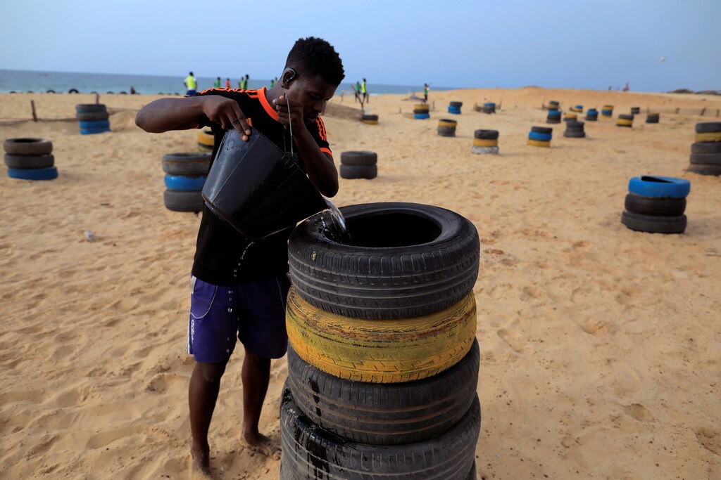 A man from Guediawaye je m'engage association waters a newly planted tree to reforest the coastline on the coast of Guediawaye on the outskirts of Dakar, Senegal.