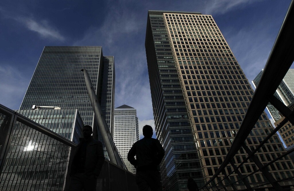 Silhouetted workers walk in front of office towers in the Canary Wharf financial district in London February 16, 2011. New Bank of England forecasts opened the door on Wednesday for interest rates to rise slowly in Britain but Governor Mervyn King warned against jumping to conclusions about when the central bank would pull the trigger. REUTERS/Luke MacGregor (BRITAIN - Tags: BUSINESS EMPLOYMENT) - RTR2IOGT