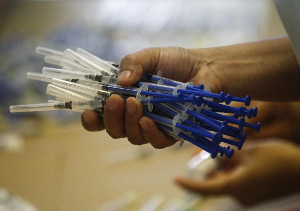 A health worker holds doses of influenza A (H1N1) vaccines in a jail in Ciudad Juarez March 29, 2011. Local health authorities have reported the reappearance of the influenza A (H1N1) virus, or swine flu, in the state of Chihuahua. So far, three people have died and another three have been reported to be infected with the virus. REUTERS/Gael Gonzalez (MEXICO - Tags: HEALTH) - GM1E73U132W01