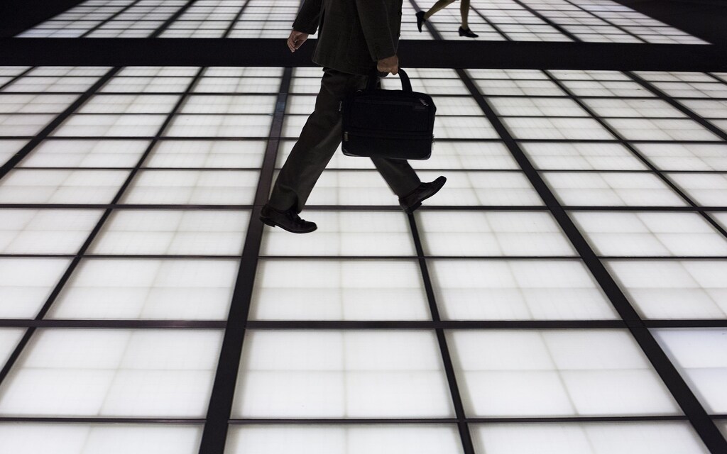 People cross an illuminated floor at a banking district in central Tokyo November 27, 2014. Japan's jobless rate fell and the availability of jobs edged higher in October from the previous month, government data released on Friday showed. Picture taken November 27, 2014.