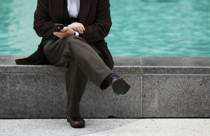 A man uses his Apple iPhone while sitting on the side of a fountain along 6th Avenue in New York, September 20, 2012. Apple's iPhone 5 goes on sale tomorrow as Apple works to increase it's market share in the mobile phone market. REUTERS/Lucas Jackson (UNITED STATES - Tags: BUSINESS SCIENCE TECHNOLOGY TELECOMS SOCIETY)