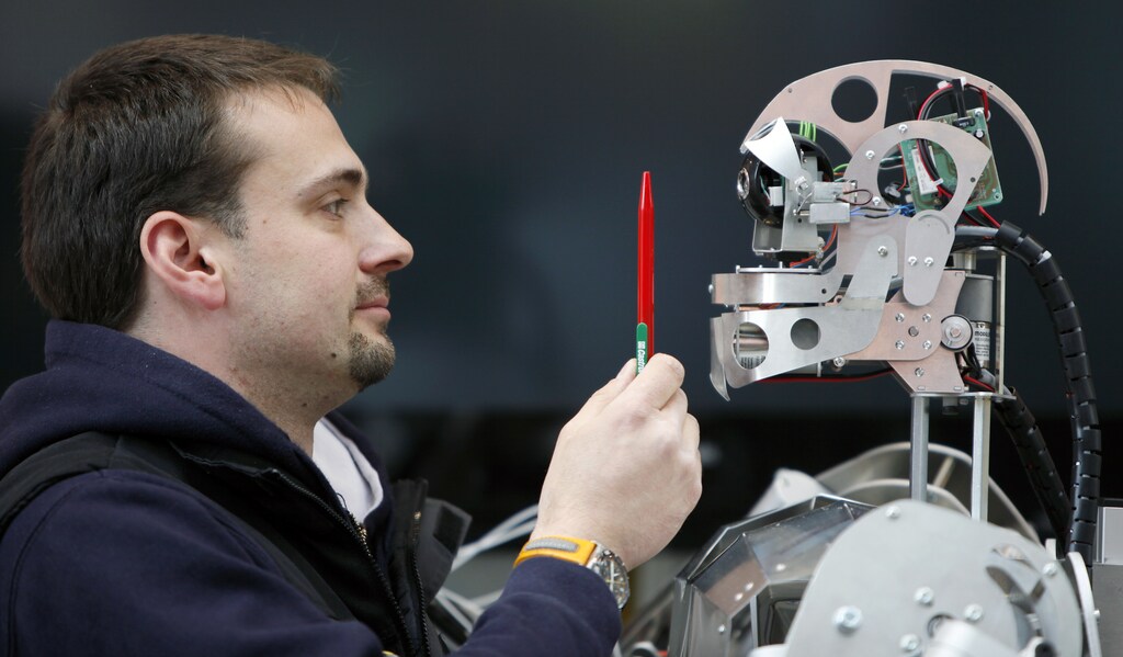 A worker sets up a robot during final preparations at the "Hannover Messe" industrial trade fair in Hanover April 19, 2009. REUTERS/Hannibal Hanschke (GERMANY SCI TECH IMAGES OF THE DAY) - BM2E54J14Y401