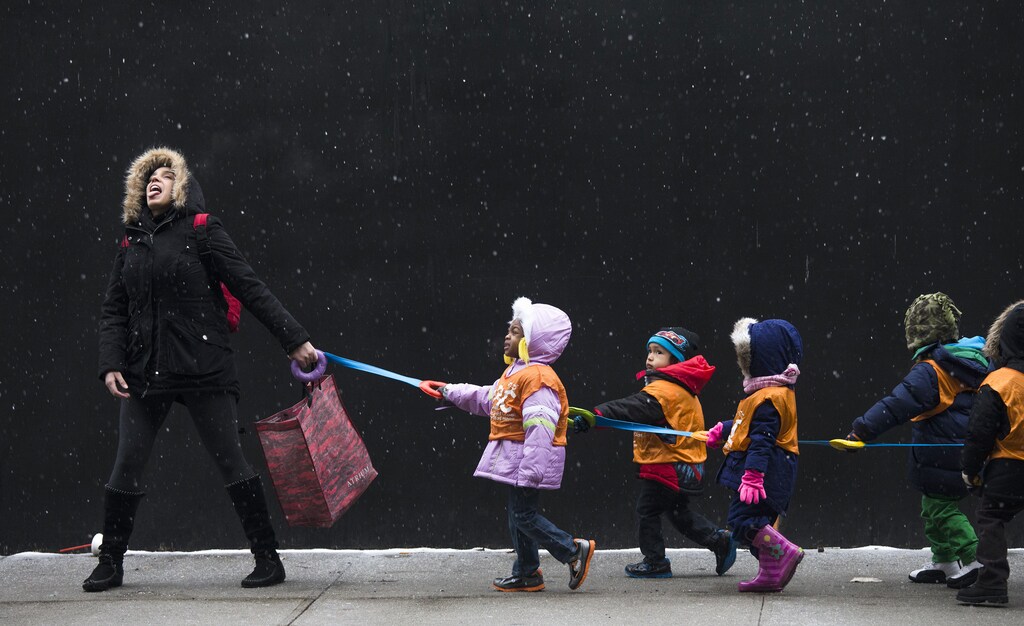 A schoolteacher, who wished to stay unidentified, attempts to catch snowflakes while leading her students to a library from school in the Harlem neighborhood, located in the Manhattan borough of New York on January 10, 2014. REUTERS/Adrees Latif (UNITED STATES - Tags: ENVIRONMENT EDUCATION TPX IMAGES OF THE DAY) - GM1EA1B00M901