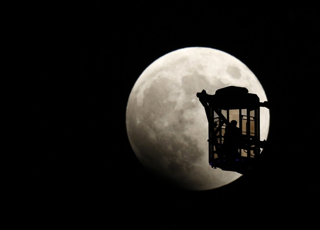 A man and a woman look at the moon as they ride a Ferris wheel, as a total lunar eclipse begins in Tokyo October 8, 2014. The eclipse is also known as a "blood moon" due to the coppery, reddish color the moon takes as it passes into Earth's shadow. The total eclipse is the second of four over a two-year period that began April 15 and concludes on Sept. 28, 2015. The so-called tetrad is unusual because the full eclipses are visible in all or parts of the United States, according to retired NASA astrophysicist Fred Espenak. REUTERS/Toru Hanai (JAPAN - Tags: SOCIETY ENVIRONMENT) - RTR49D49