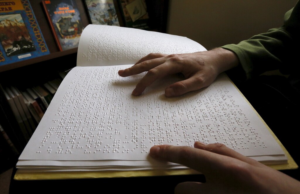 A visitor reads a book written in Braille at a specialized library for blind and partially sighted people in Krasnoyarsk, Siberia, Russia, March 15, 2016. REUTERS/Ilya Naymushin