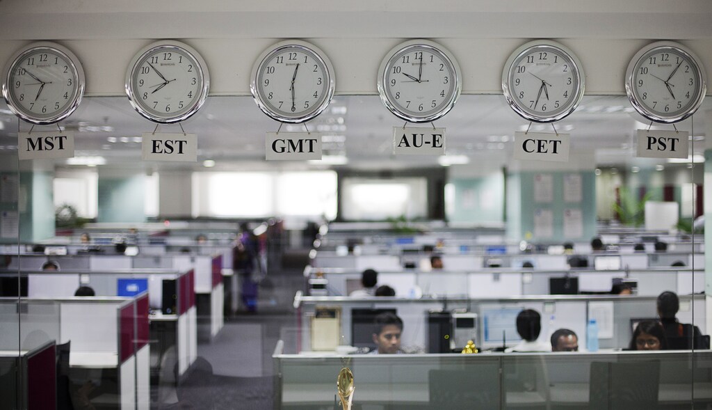 Workers are pictured beneath clocks displaying time zones in various parts of the world at an outsourcing centre in Bangalore, February 29, 2012. India's IT industry, with Bangalore firms forming the largest component, is now worth an annual $100 billion and growing 14 percent per year, one of the few bright spots in an economy blighted by policy stagnation and political instability. Picture taken on February 29, 2012. To match Insight INDIA-OUTSOURCING/ REUTERS/Vivek Prakash (INDIA - Tags: BUSINESS EMPLOYMENT SCIENCE TECHNOLOGY) - RTR30CVG
