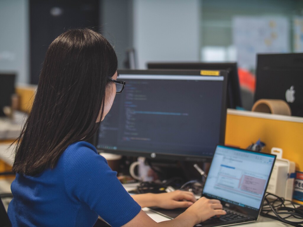 Woman wearing glasses looking at a laptop.