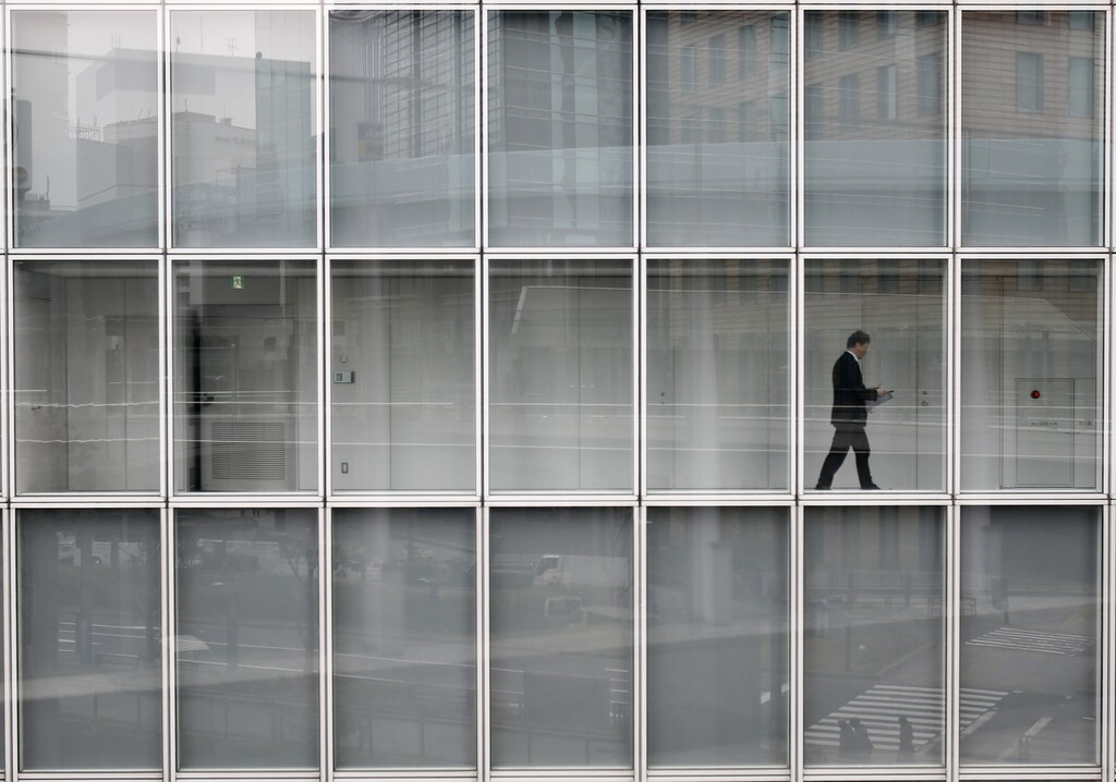 A man walks inside an office building in Tokyo March 19, 2014. Large Japanese firms are growing more confident about weathering the impact of an imminent sales tax increase and they expect further profit rises even after a bumper year, a Reuters poll showed - encouraging signs for an economy that is seeing a sharp slowdown in growth. REUTERS/Yuya Shino (JAPAN - Tags: BUSINESS POLITICS EMPLOYMENT TPX IMAGES OF THE DAY) - RTR3HT6J