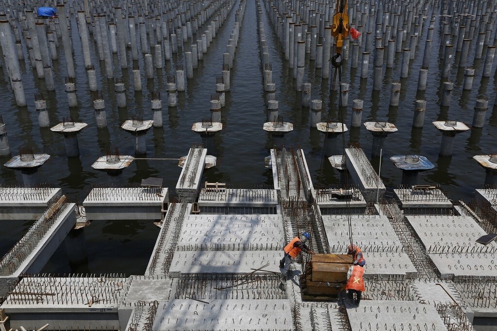 Workers toil at the construction site of a new pier at New Priok container terminal in north Jakarta, November 26, 2014. Needing some $450 billion spent on Indonesia's infrastructure by 2019, new President Joko Widodo has ordered ministers to give private investors first pick of money-making projects rather than let state agencies grab them as they usually do. Hitherto, the government's contracting agencies got first choice of which airports, railways, toll-roads and other pieces of infrastructure to build. The ones they didn't want were offered to the private sector. Picture taken November 26, 2014. REUTERS/Beawiharta (INDONESIA - Tags: BUSINESS EMPLOYMENT TPX IMAGES OF THE DAY) - GM1EABR1K0L01