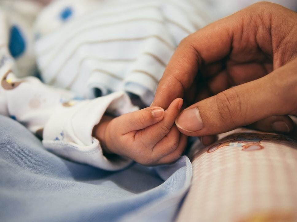 image of a woman's hand holding a newborn baby's hand