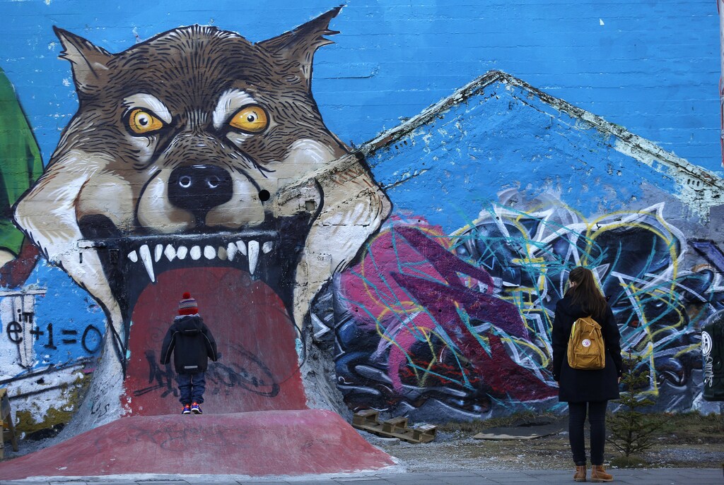 A woman and child walk next to graffiti in downtown Reykjavik February 16, 2013. Iceland's biggest IT company CCP is what the island needs to leave its economic crisis behind. It is global, growing and employs hundreds but its tale is also one of frustration that echoes concerns about the country's future. Many expected Iceland's recovery to be stronger given the way smaller economies can bounce from deep recessions. The International Monetary Fund had originally forecast annual growth of around 4.5 percent from 2011-2013. It now is under half that. Picture taken February 16, 2013. To match Analysis ICELAND-ECONOMY/ REUTERS/Stoyan Nenov (ICELAND - Tags: BUSINESS EMPLOYMENT SOCIETY SCIENCE TECHNOLOGY) - GM1E92L1QVB01