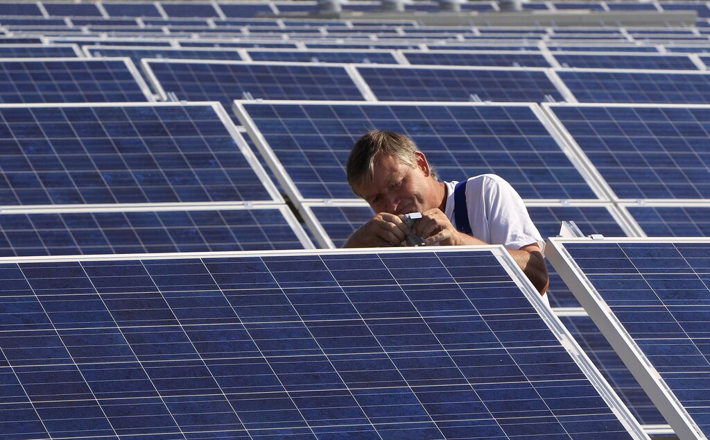 Un trabajador de la construcción instala paneles solares para una nueva planta de energía solar cerca de Olching-Esting, al oeste de Múnich.