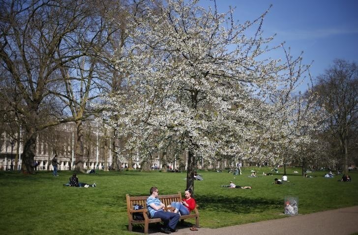 A couple sit under a tree on a warm spring day in St James's Park in central London April 23, 2013. REUTERS/Andrew Winning (BRITAIN - Tags: CITYSCAPE ENVIRONMENT SOCIETY)
