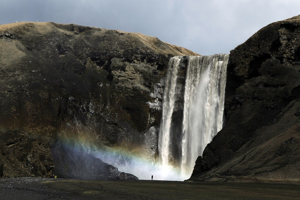 A woman stands near a waterfall that has been dirtied by ash that has accumulated from the ash plume of an erupting volcano near Eyjafjallajokull, Iceland April 18, 2010.