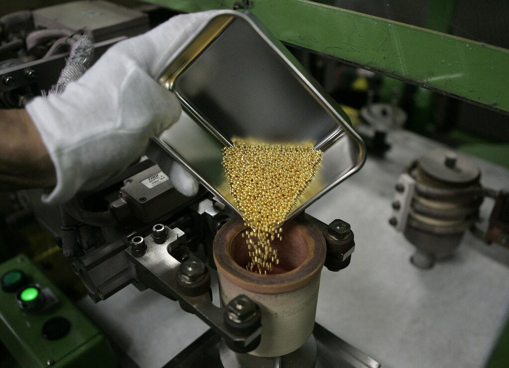 Gold granules are poured by a worker into a crucible before being formed into a gold bar at a Tanaka Kikinzoku Kogyo factory in Kanagawa Prefecture August 20, 2009. The factory produces gold bars and gold products for industrial and commercial use, and recycles gold from old products such as jewellery and industrial scrap. REUTERS/Michael Caronna (JAPAN BUSINESS) - GM1E58K1H8G01