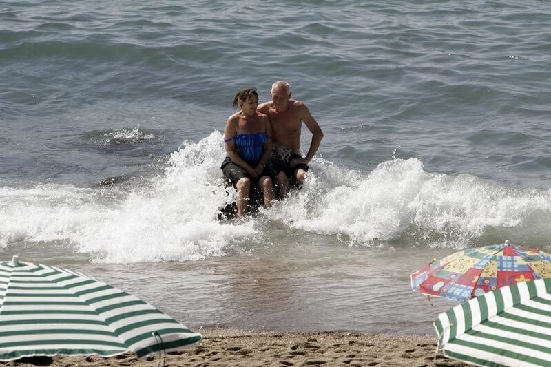 A couple sits at Bil Bil beach in the southern Spanish town of Benalmadena, September 1, 2008. Few Spaniards would sacrifice their annual summer holiday, but while beaches are packed, shops and restaurants are omminously quiet as Spain's deepening economic crisis envelopes the sector.