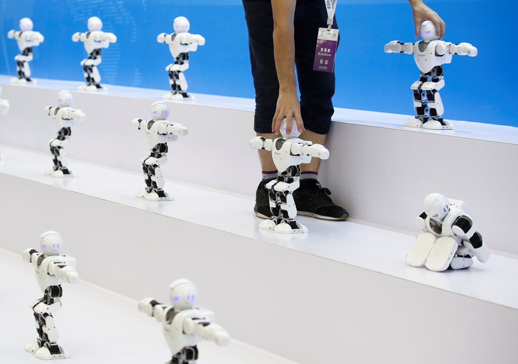 A man lines up robots for the performance of a syncronised dance at the 2017 World Robot Conference in Beijing, China August 22, 2017. REUTERS/Thomas Peter - RC1A2941C9F0
