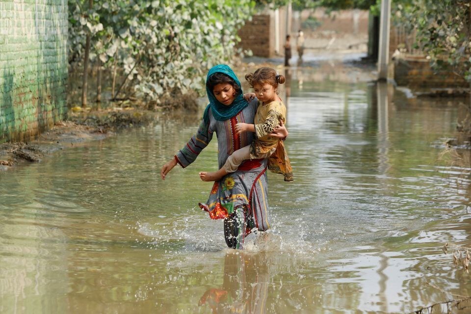 A girl carries a younger girl through flood water in Nowshera, Pakistan.