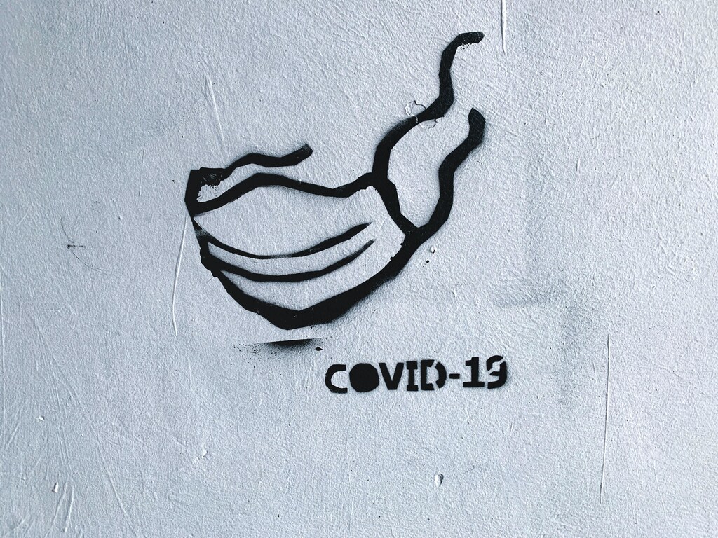 A face covering and COVID-19 painted on a wall