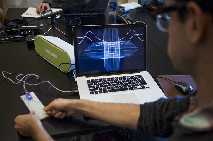 Peter Kirn holds two coins between his fingers to create sounds with a synthesizer in Berlin, July 19, 2012. Kirn makes music with an unusual instrument - his own body. The Kentucky native pinches two electrically charged pennies connected to a laptop, measuring the electrical currents of his body and synthesise them into melodic sound. The laptop screen shows a visualisation of the sound he is creating. REUTERS/Thomas Peter (GERMANY - Tags: ENTERTAINMENT SOCIETY)