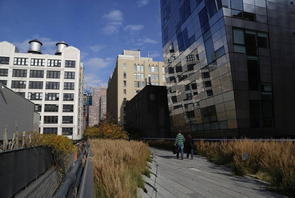 People walk along High Line park on a warm autumn day in New York November 11, 2014. The High Line, renovated into a public park, was formerly an elevated railway 30 feet above the city's West Side that was built in 1934 for freight trains hauling dairy products, produce and meats and had become derelict after the rail closed in 1980. REUTERS/John Schults (UNITED STATES - Tags: ENVIRONMENT SOCIETY CITYSCAPE) - GM1EABC1B7I01