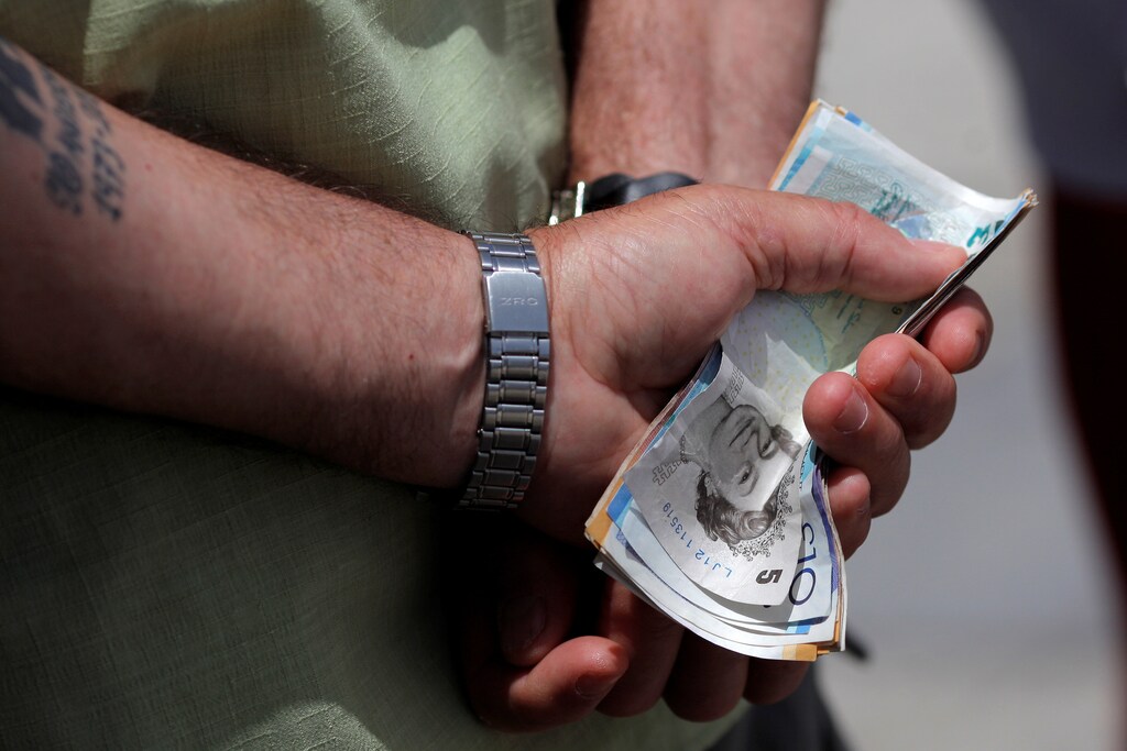 A man holds various English Pound notes as he waits in line to exchange it for Euros notes outside a money exchange office in the British overseas territory of Gibraltar, historically claimed by Spain, June 24, 2016, after Britain voted to leave the European Union in the EU BREXIT referendum. REUTERS/Jon Nazca - S1AETLTXIYAA