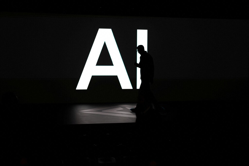 Someone looking at their phone walks past a big "AI" sign.