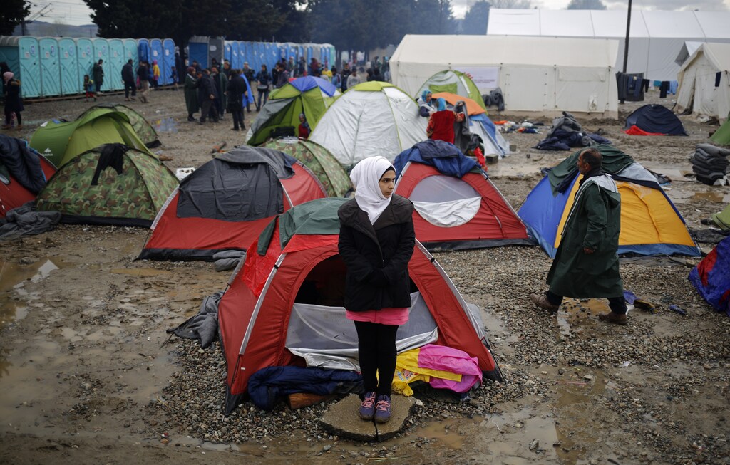 A migrant woman stands outside a tent at a makeshift camp on the Greek-Macedonian border near the village of Idomeni, Greece March 10, 2016.