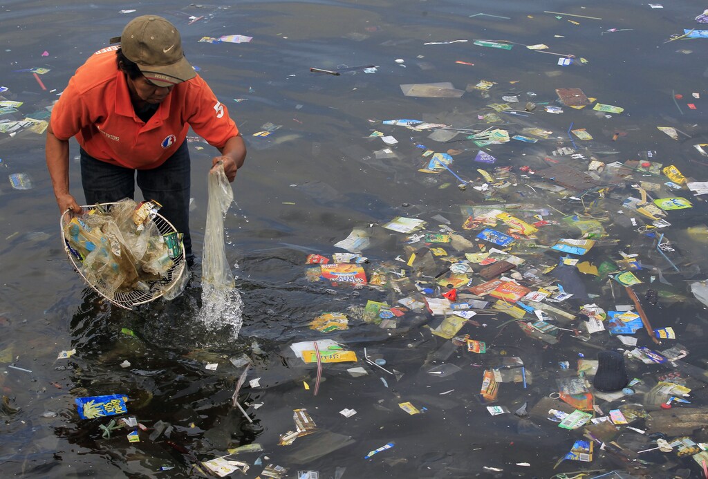 A government sanitary worker collects and segregates garbage in Manila bay