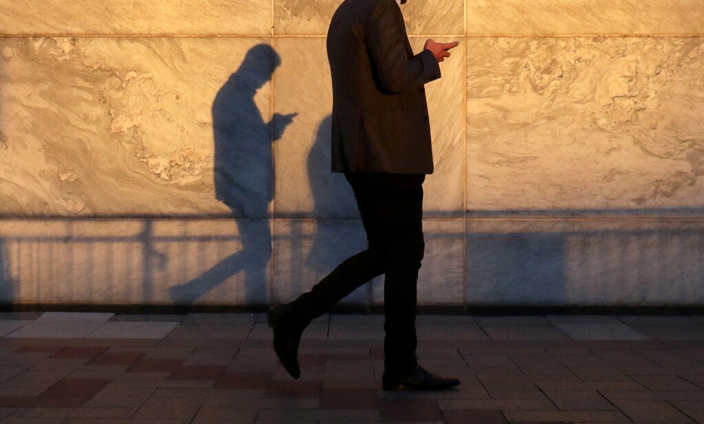 An unidentified man using a smart phone walks through London's Canary Wharf financial district in the evening light in London, Britain, September 28, 2018. REUTERS/Russell Boyce TPX IMAGES OF THE DAY - RC1B87E033F0