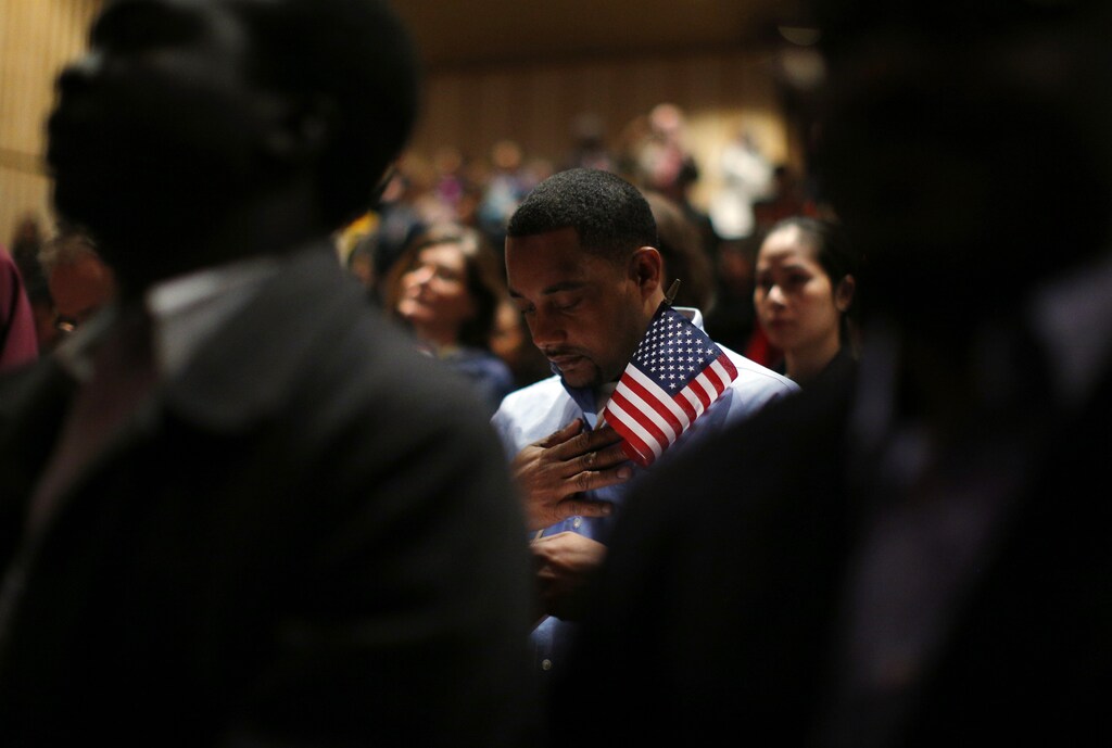Immigrants stand for the invocation during a naturalization ceremony to become new U.S. citizens at Boston College in Chestnut Hill, Massachusetts March 21, 2013.