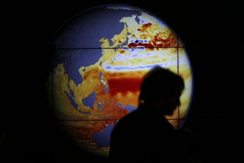 A woman walks past a map showing the elevation of the sea in the last 22 years during the World Climate Change Conference 2015 (COP21) at Le Bourget, near Paris, France, December 11, 2015. REUTERS/Stephane Mahe TPX IMAGES OF THE DAY - LR1EBCB148RZ4