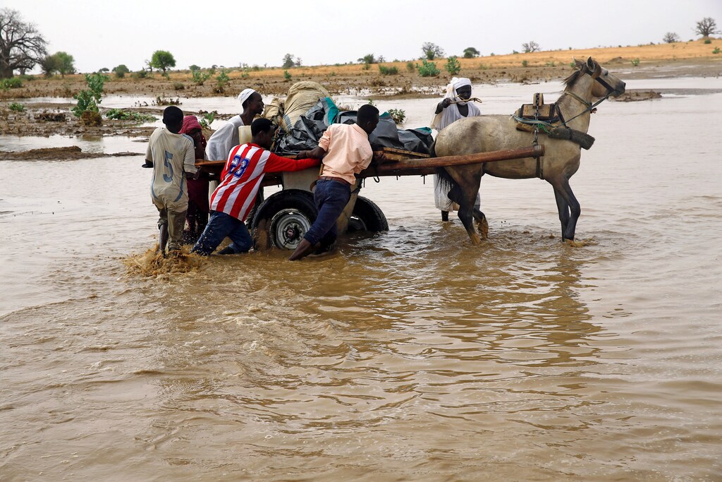 displaced people carry their belongings to get away from flood during heavy rain at Nyala locality in South Darfur, Sudan