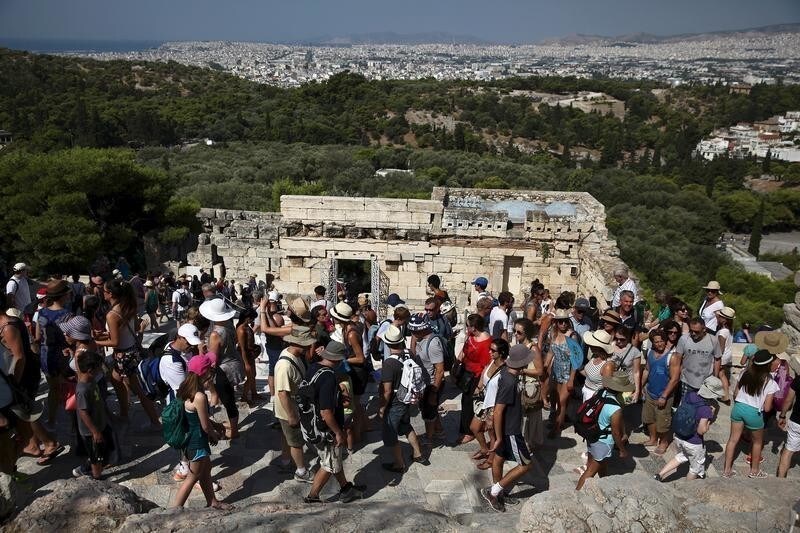 Tourists make their way in front of the Propylaia at the archaeological site of the Acropolis hill in Athens, Greece August 4, 2015. Hard numbers for tourist arrivals in Greece are difficult to come by because it is only just high season, but there are signs.Aegean Airlines, Greece's largest carrier, says passenger traffic was up 19 percent in July compared with the same month last year. Picture taken August 4, 2015.