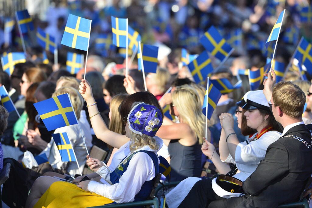 People in the audience wave Swedish flags during the traditional National Day celebrations with the royal family at Skansen in Stockholm June 6, 2013. REUTERS/Henrik Montgomery/Scanpix