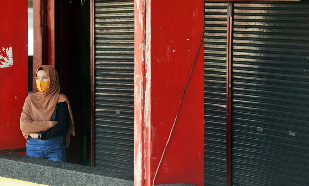 A woman wearing a protective mask stands near a closed shop amid the coronavirus disease (COVID-19) outbreak in Padang, West Sumatra Province, Indonesia, April 20, 2020, in this photo taken by Antara Foto. Antara Foto/Iggoy el Fitra/ via REUTERS ATTENTION EDITORS - THIS IMAGE WAS PROVIDED BY A THIRD PARTY. MANDATORY CREDIT. INDONESIA OUT. - RC298G9K28L0