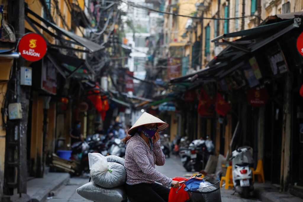 A woman wears a protective mask as she rides past an empty street during the coronavirus disease (COVID-19) outbreak in Hanoi, Vietnam March 26, 2020. vietnam nviet nam asia Coronavirus china virus health healthcare who world health organization disease deaths pandemic epidemic worries concerns Health virus contagious contagion viruses diseases disease lab laboratory doctor health dr nurse medical medicine drugs vaccines vaccinations inoculations technology testing test medicinal biotechnology biotech biology chemistry physics microscope research influenza flu cold common cold bug risk symptomes respiratory china iran italy europe asia america south america north washing hands wash hands coughs sneezes spread spreading precaution precautions health warning covid 19 cov SARS 2019ncov wuhan sarscow wuhanpneumonia pneumonia outbreak patients unhealthy fatality mortality elderly old elder age serious death deathly deadly