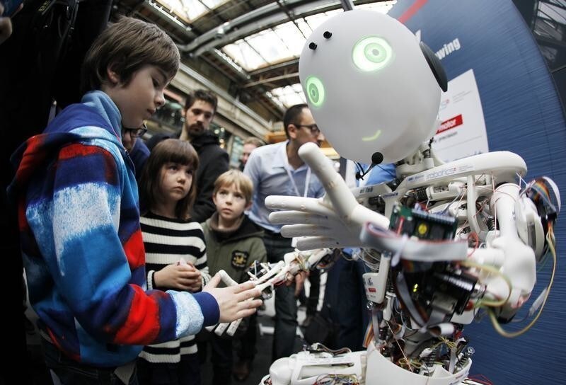 Children interact with the humanoid robot Roboy at the exhibition Robots on Tour in Zurich, March 9, 2013. A project team composed of scholars and industry representatives developed the prototype of the tendon driven humanoid robot Roboy within nine months. Roboy was unveiled to the public today during the exhibition that is marking the 25th anniversary of the Artificial Intelligence Laboratory of the University of Zurich (AI Lab). Picture taken with fish-eye lens. REUTERS/Michael Buholzer (SWITZERLAND - Tags: SCIENCE TECHNOLOGY SOCIETY BUSINESS) - BM2E93916CJ01