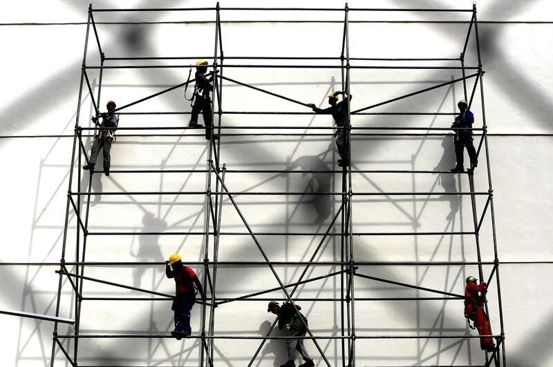 Workers stand on a scaffolding outside Maracana stadium in Rio de Janeiro June 6, 2014. , In a project called OnThe Sidelines' Reuters photographers share pictures showing their own quirky and creative view of the 2014 World Cup in Brazil. REUTERS/Tont Gentile REUTERS - RTR3SPXS