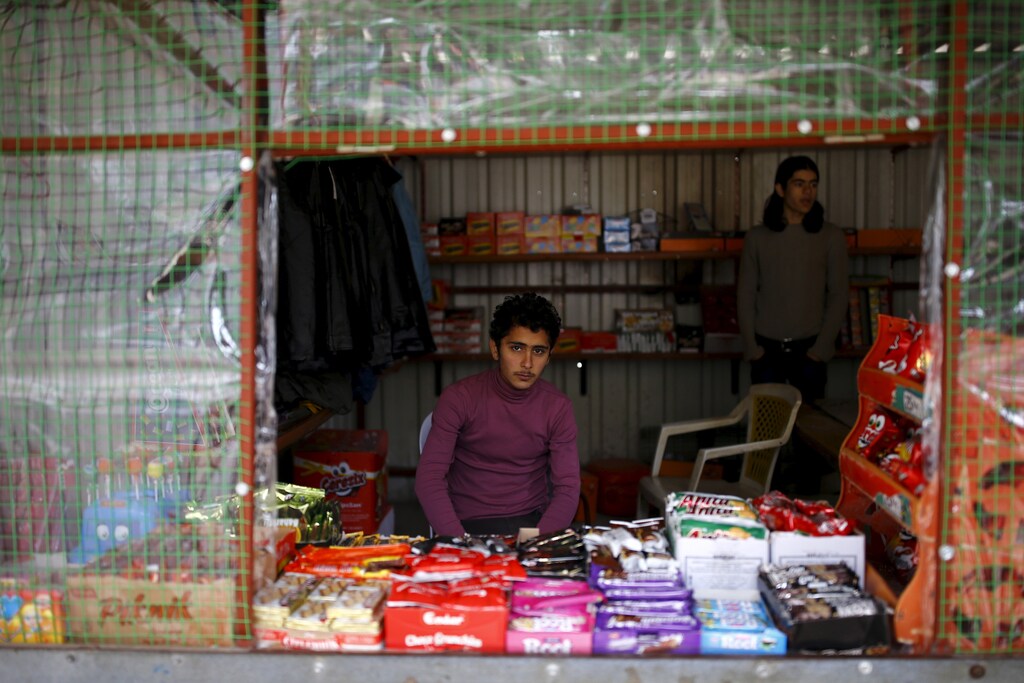 Syrian refugee Resad Bekur, 18, poses in a shop where he works in Yayladagi refugee camp in Hatay province, near the Turkish-Syrian border, Turkey, December 16, 2015. Syria's conflict has left hundreds of thousands dead, pushed millions more into exile, and had a profound effect on children who lost their homes or got caught up in the bloodletting. The drawings of young refugees living in Turkey show their memories of home and hopes for its future. The pictures also point to the mental scars borne by 2.3 million Syrian refugees living in Turkey, more than half of them children. REUTERS/Umit Bektas - GF20000092551