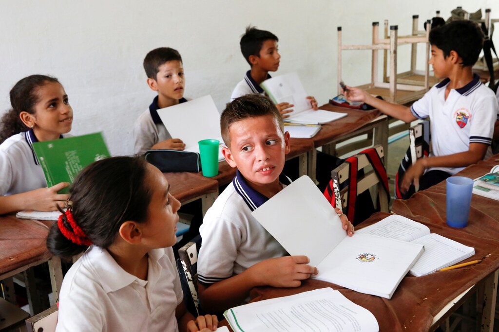 Children use their books to fan themselves during a class at an improvised classroom in a garage of a house, which is part of state school Monsenor Marco Tulio Ramirez Roa, in La Fria, Venezuela, June 1, 2016. REUTERS/Carlos Garcia Rawlins SEARCH "VENEZUELA SCHOOL" FOR THIS STORY. SEARCH "THE WIDER IMAGE" FOR ALL STORIES - RTX2GM2C