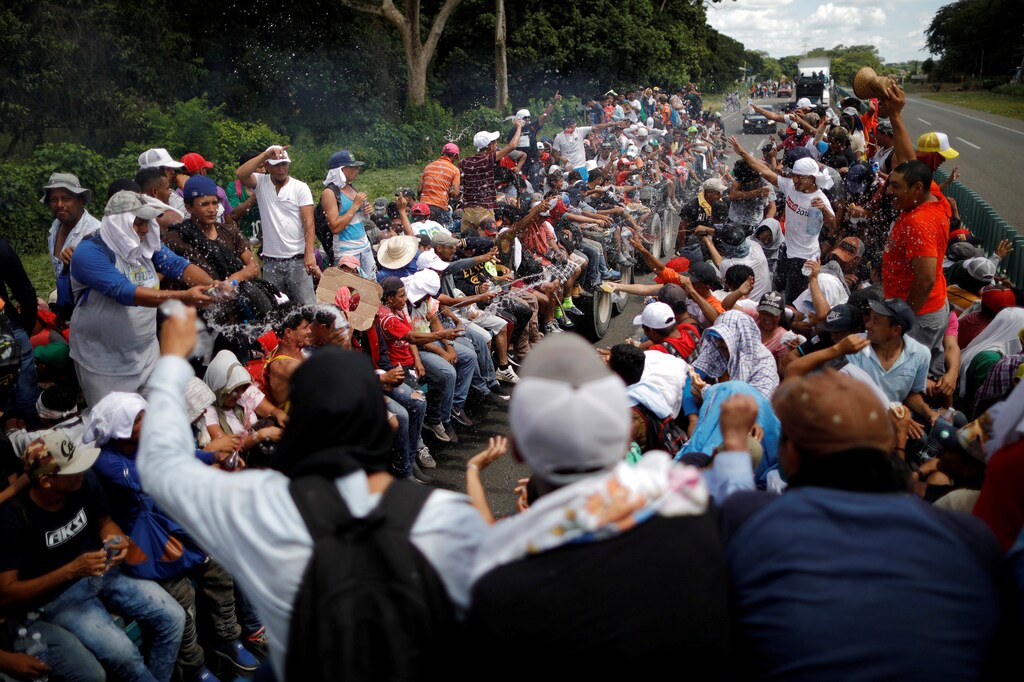 Central American migrants, who are part of a caravan of migrants trying to reach the United States, hitchhike on a truck along the highway as they continue their journey in Tapachula, Mexico, October 22, 2018. Reuters photographer Ueslei Marcelino: "With a journey of thousands of kilometres the migrants hitchhiked on trucks as much as they could. I decided to climb one of these trucks to accompany a group of Hondurans as they continued their journey. Here, one truck full of migrants, drives past another. People greeted one another by throwing water as a way of celebrating their luck at catching a ride." REUTERS/Ueslei Marcelino SEARCH "IMMIGRATION POY" FOR THIS STORY. SEARCH "REUTERS POY" FOR ALL BEST OF 2018 PACKAGES. TPX IMAGES OF THE DAY. - RC13CD3EE500