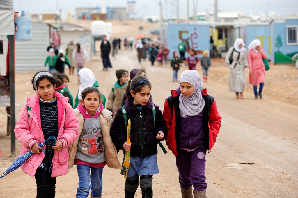 Syrian refugee children walk to the school during rainy weather at the Al Zaatari refugee camp in the Jordanian city of Mafraq, near the border with Syria December 18, 2016. REUTERS/Muhammad Hamed - RTX2VJMJ